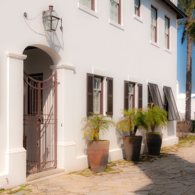 white masonry walls of Alys Beach on Florida's Design Coast sit on subtle masonry base, trimmed with palms sitting in tall terra cotta pots