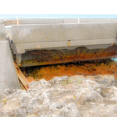 rusted steel reinforcing bars hang grotesquely out of the crumbling remains of a highway bridge in the Bahamas that endured too much salt spray