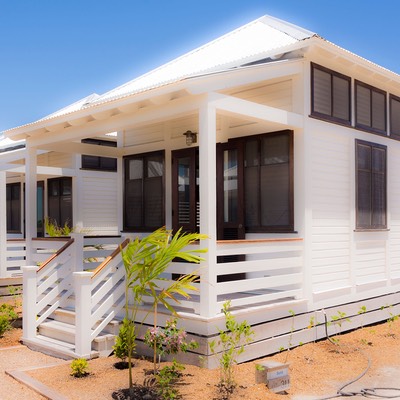 front porch of newly-built whitewashed cottage sits against balmy blue tropical sky at Mahogany Bay Village