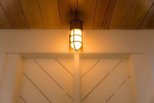 vapor-proof ship's light glowing softly against the open walls of the Dream Suite in Mahogany Bay Village, with diagonal wind sheathing providing both strength and visual interest