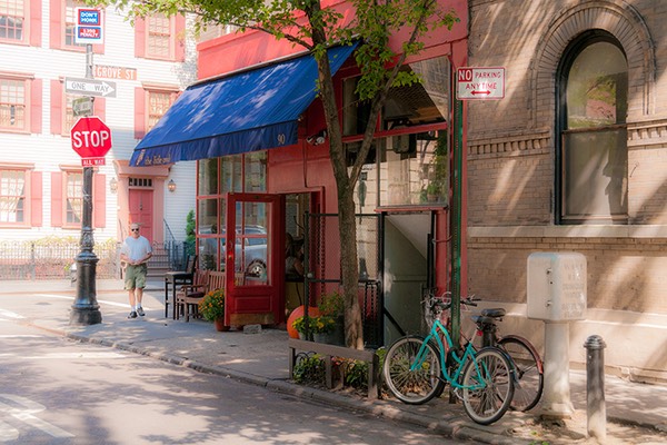 two bikes stand waiting for their owners just outside blue-awninged Greenwich Village corner eatery